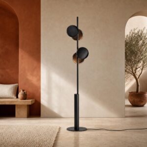 Un lampadaire moderne à disques noirs style éclipse dans une pièce aux teintes beige et terracotta avec un banc un bois et un arbuste dans le fond.