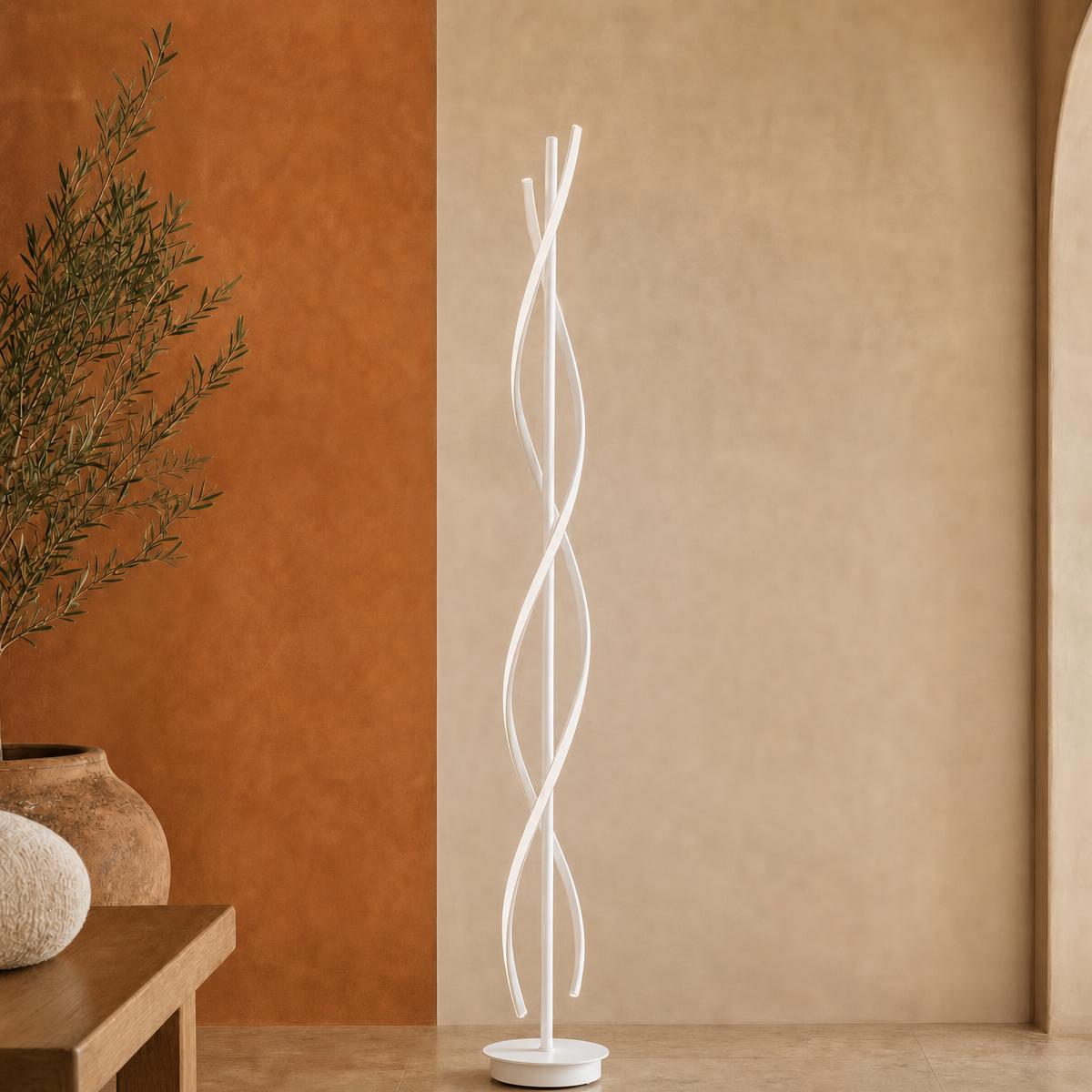 Un lampadaire LED moderne en double spirale blanc, posé dans un salon au mur beige et terracotta.